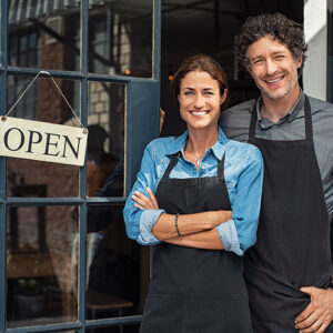 Two smiling small business owners posing for a photo outside of their business